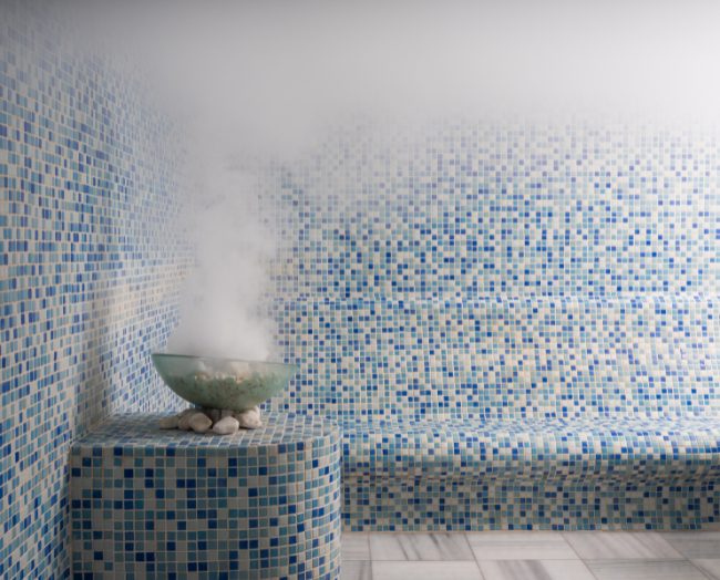 Blue mosaic tile steam room with a curved bench and tiled floor
